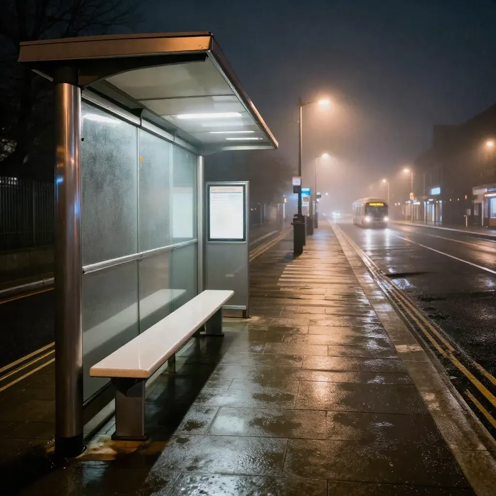 Empty UK bus stop, zebra crossing and distant station glow in night mist